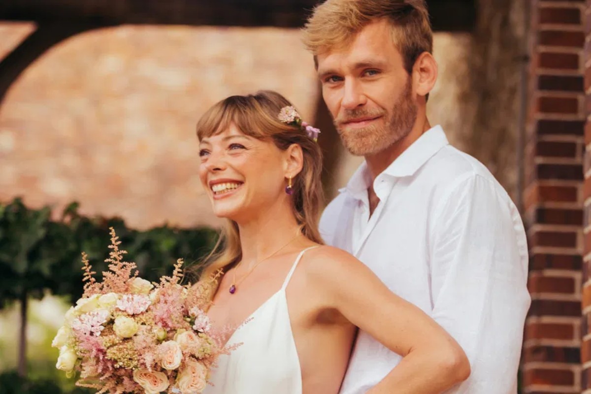 Couple souriant et enlacé, tenant un bouquet de fleurs pastel, symbolisant la douceur et l’amour des noces de rose